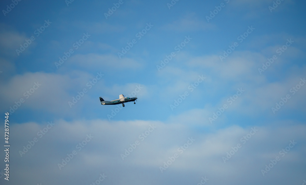 Cessna 208b Grand Caravan G-CPSS light aircraft climbing in a blue and white cloud sky