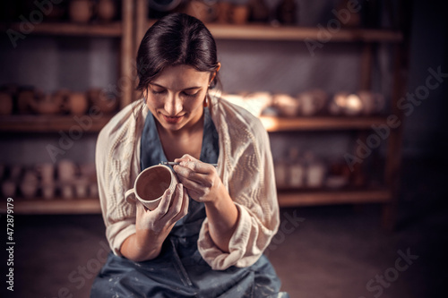 Stylish female master enjoying pottery art and production process. Making pottery. photo