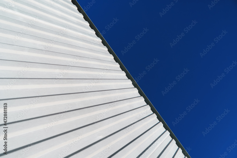 Textured white metal structures diagonally against a blue sky. Textured white metal structures diagonally against a blue sky.