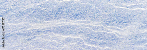 Snowy background, snow-covered surface of the earth after a blizzard in the morning in the sunlight with distinct layers of snow