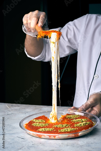 Arabian Traditional Desserts - Cream and cheeses with pistachio flavor and nuts topping on gray background photo