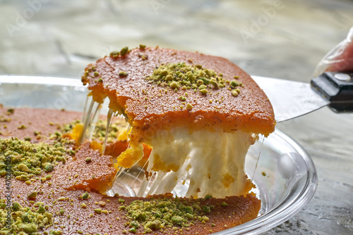 Arabian Traditional Desserts kunafa - Cream and cheeses with pistachio flavor and nuts topping on gray background photo
