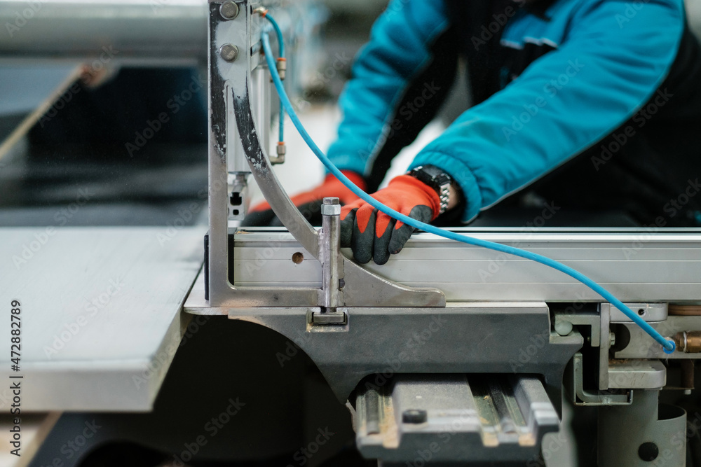 Cnc circular saw sawing chipboard. Process of making cabinet furniture close-up. Worker with gloves at the machine. Cnc circular saw sawing chipboard. Process of making cabinet furniture close-up. Worker with gloves at the machine.