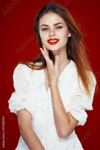 cheerful red-haired woman with red lips white dress red background