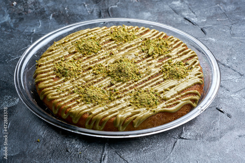 Arabian Traditional Desserts Kanafa - Cream and cheeses with pistachio flavor and nuts topping on gray background