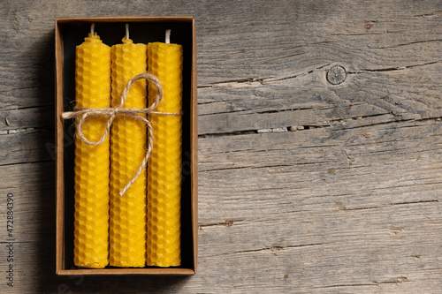 Yellow beeswax candles in a cardboard box, top view. Copy space for text. photo