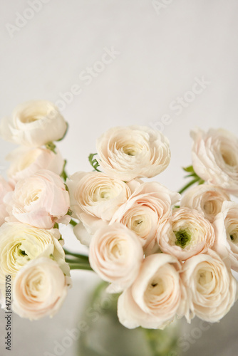 The background of ranunculus colors is gently pink. A riotous peony-shaped rose bouquet