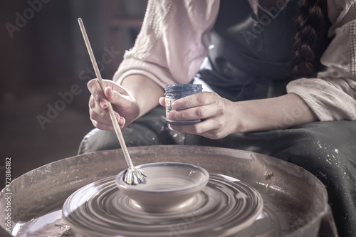 Creating vase of white clay close-up. The sculptor in the workshop makes a jug out of earthenware closeup. Twisted potter's wheel. photo