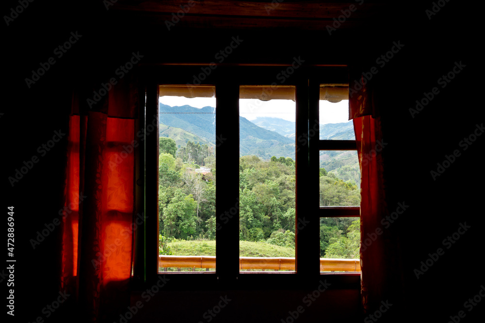 Horizontal front view of window frame with nature landscape in background. Horizontal view of green mountains scenery from a window frame. Travel destinations in Colombia