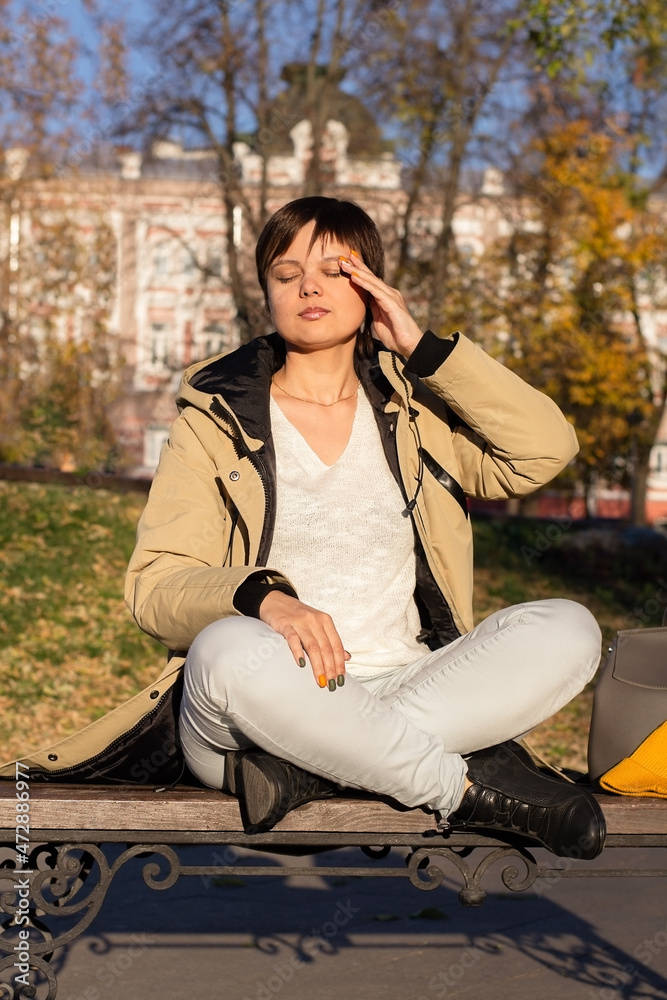 Young woman sits cross-legged and holds her head with her hand with closed eyes. Selective focus Young woman sits cross-legged and holds her head with her hand with closed eyes. Selective focus