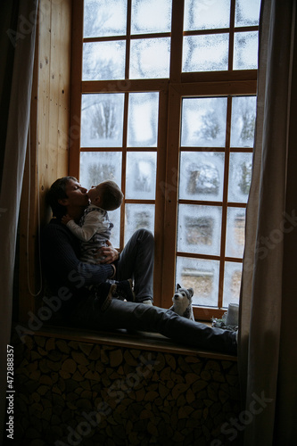 dad and son are sitting on the windowsill against the background of the window