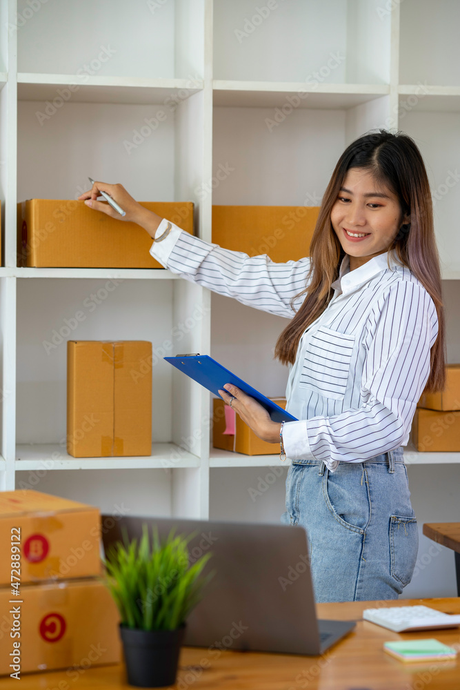 Portrait of Asian young woman SME working with a box at home the workplace.start-up small business owner, small business entrepreneur SME or freelance business online and delivery concept. Portrait of Asian young woman SME working with a box at home the workplace.start-up small business owner, small business entrepreneur SME or freelance business online and delivery concept.