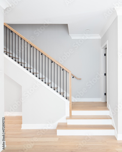 Fotobehang A staircase going up with natural wood steps and handrails, white risers, and wrought iron spindles