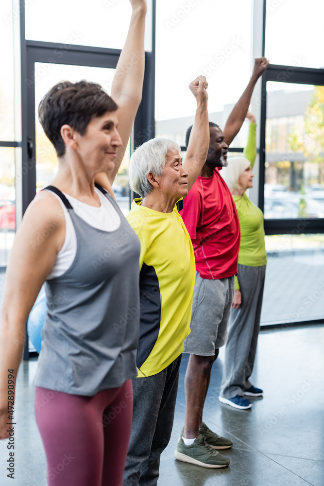 Obraz premium Elderly asian man training near multiethnic friends in sports center.