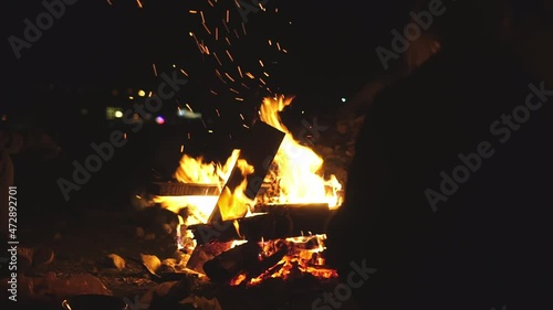 a young guy and a girl are sitting on folding chairs by the fire and talking. At night, two travelers made a stop in nature and are warming themselves from the cold by the fire. photo