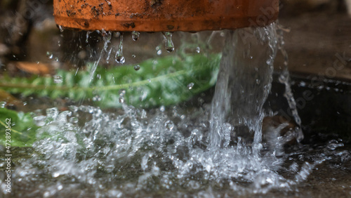Close-up view of raindrops flowing down from the pipeline. A stream of water flows from the roof through a pipe.