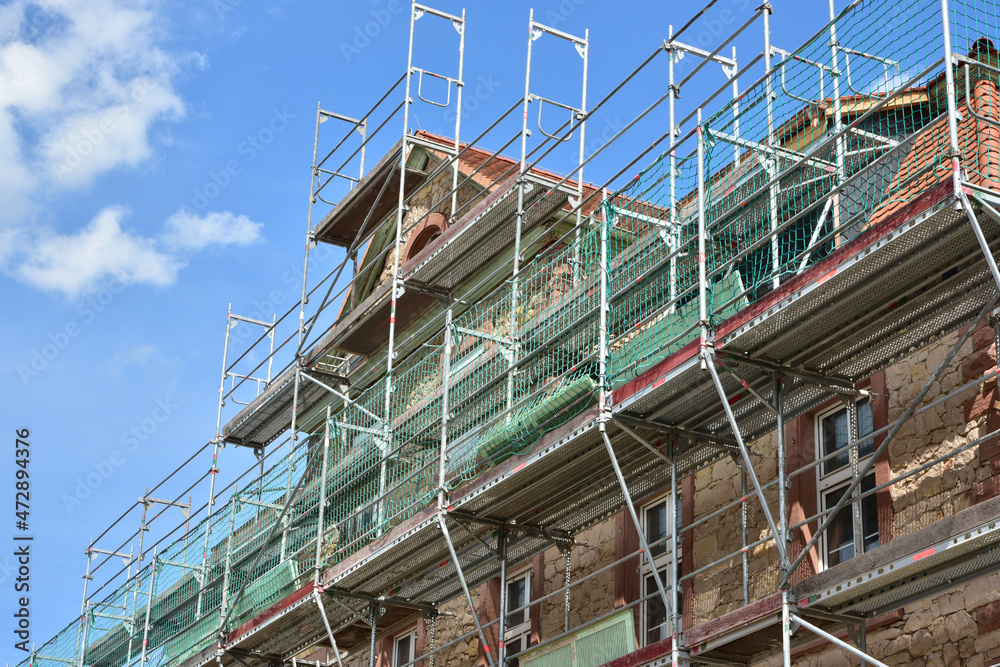 Gerüst für die Renovierung der denkmalgeschützten Fassade eines älteren Gebäudes mit Sicherheitsnetz Gerüst für die Renovierung der denkmalgeschützten Fassade eines älteren Gebäudes mit Sicherheitsnetz