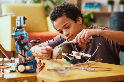 Smart African boy making a robot at home for science class. Robotics and education.