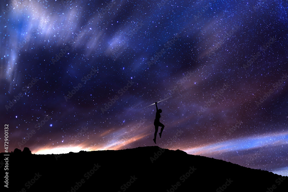 Girl silhouette jumping above the hill in the starry night. Bright milky way galaxy behind her.