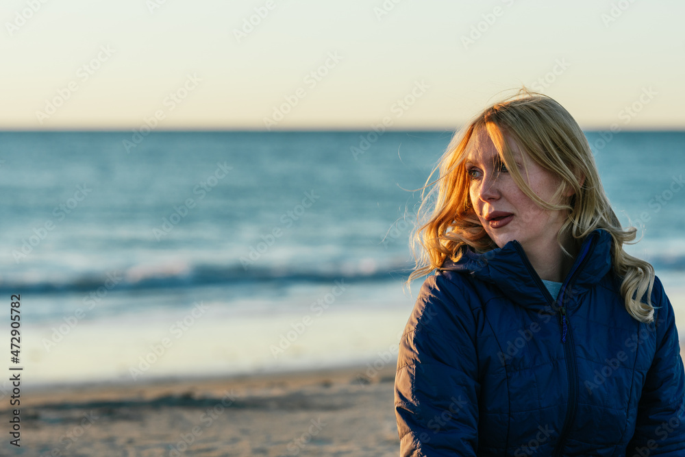 Blonde woman with relaxed expression on a beach during sunset Blonde woman with relaxed expression on a beach during sunset
