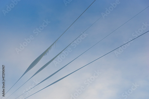 Snow, ice and icicles on wires on blue sky