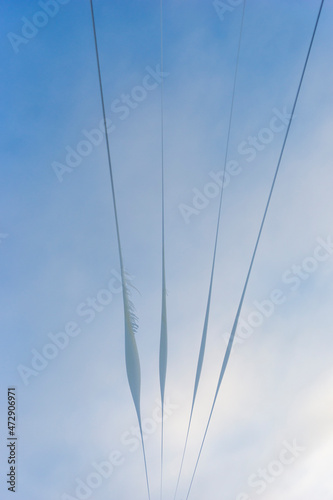 Snow, ice and icicles on wires on blue sky