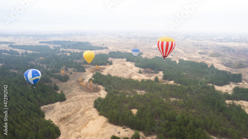 Air baloon flying above the green forest and sand of desert