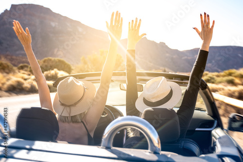 Fotografía Dreams come true! Two happy young girls driving cabrio car during vacation road trip in mountains, making memories and having fun together