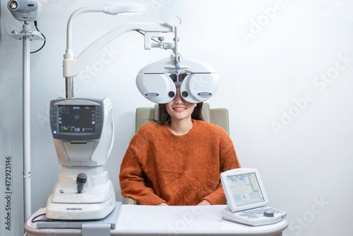 Картината върху платно Asian beautiful woman looking through auto refractometer in modern ophthalmology