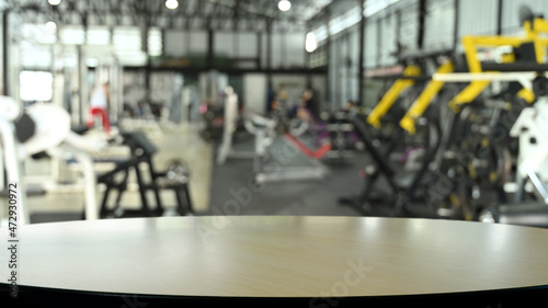 Wooden empty table on blurred background of fitness gym. Copy space for display of product.