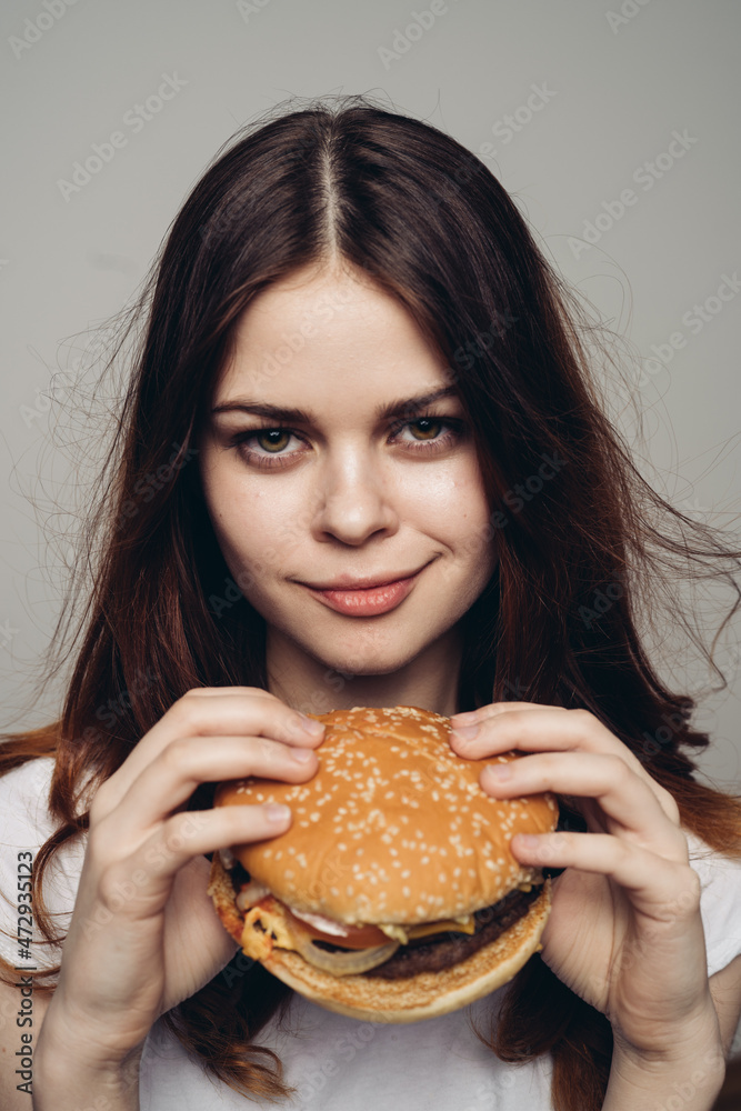 woman with a hamburger in her hands a snack fast food close-up woman with a hamburger in her hands a snack fast food close-up