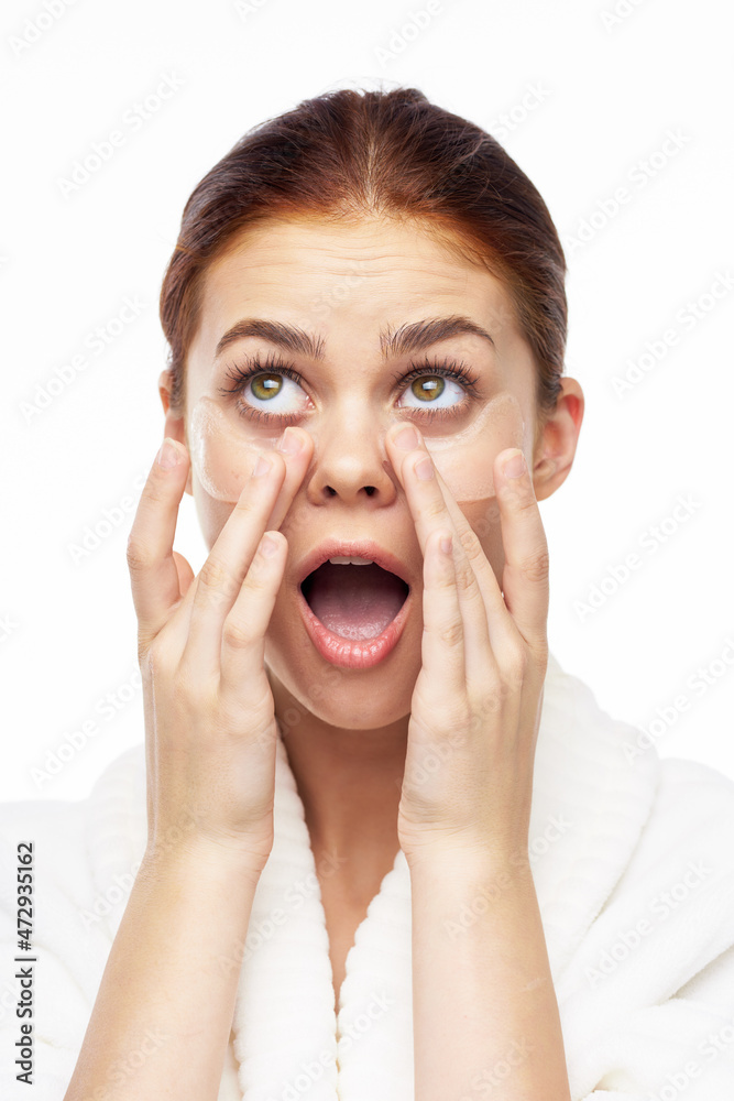 Woman in white robe posing fun skin care patches on face Woman in white robe posing fun skin care patches on face