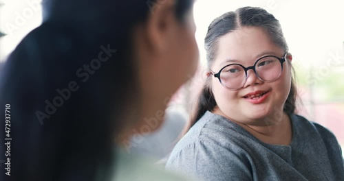 Back view of unrecognizable woman hugging cute girl with down syndrome and expressing love whie sitting on couch at home