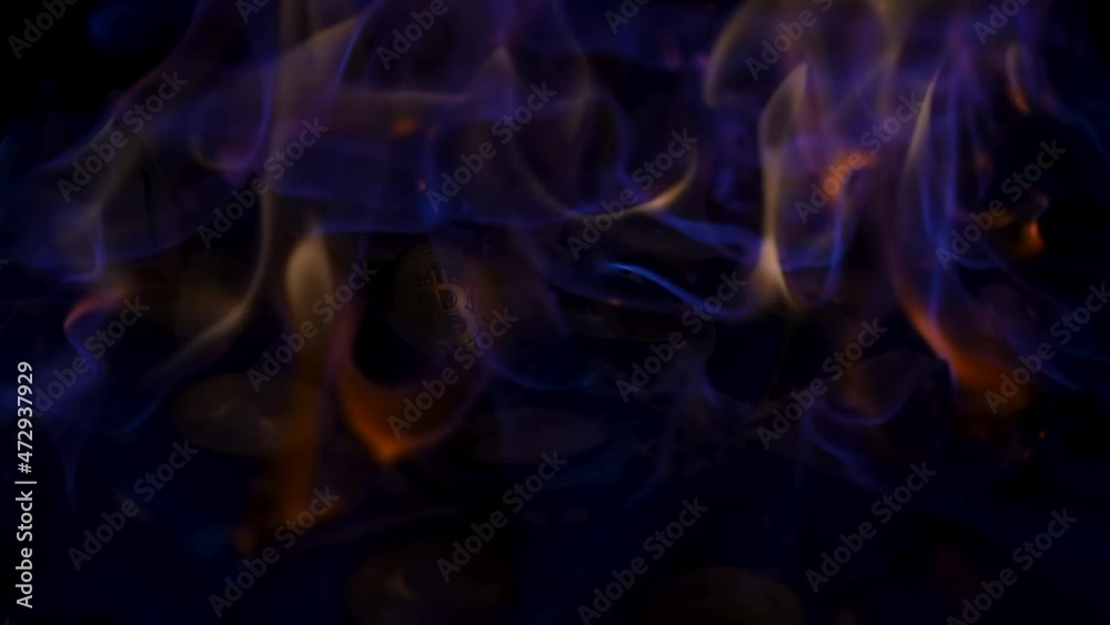 A bright fire burning crumpled paper dollar bills and gold bitcoin coins. Money lights up and burns, banknotes usd enveloped in tongues of flame, ccryptocurrency is set on fire. Close up, slow motion. A bright fire burning crumpled paper dollar bills and gold bitcoin coins. Money lights up and burns, banknotes usd enveloped in tongues of flame, ccryptocurrency is set on fire. Close up, slow motion.