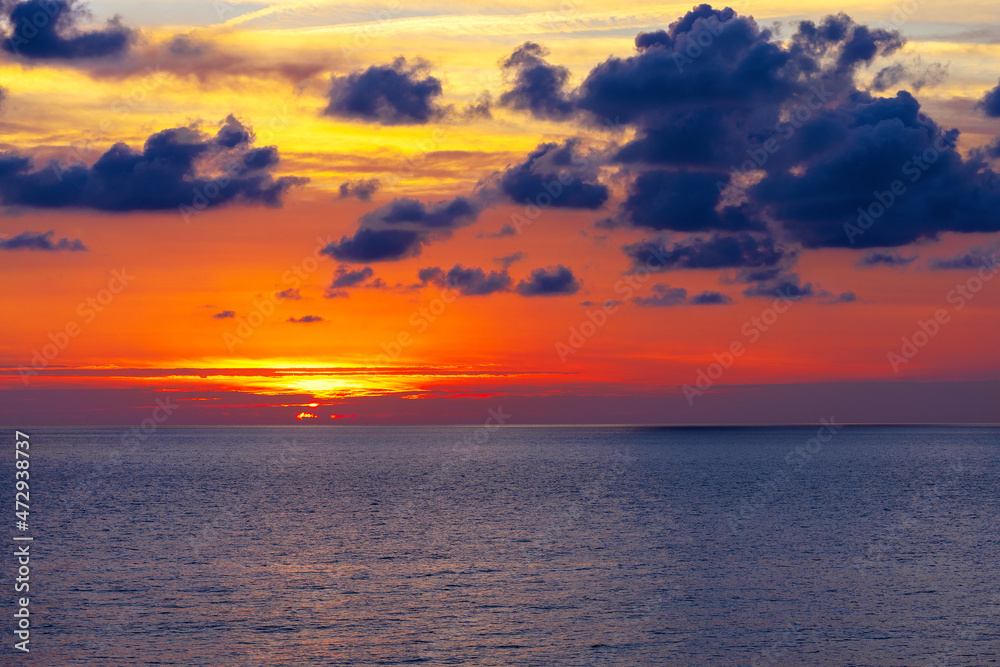 The sun setting over the sea horizon.