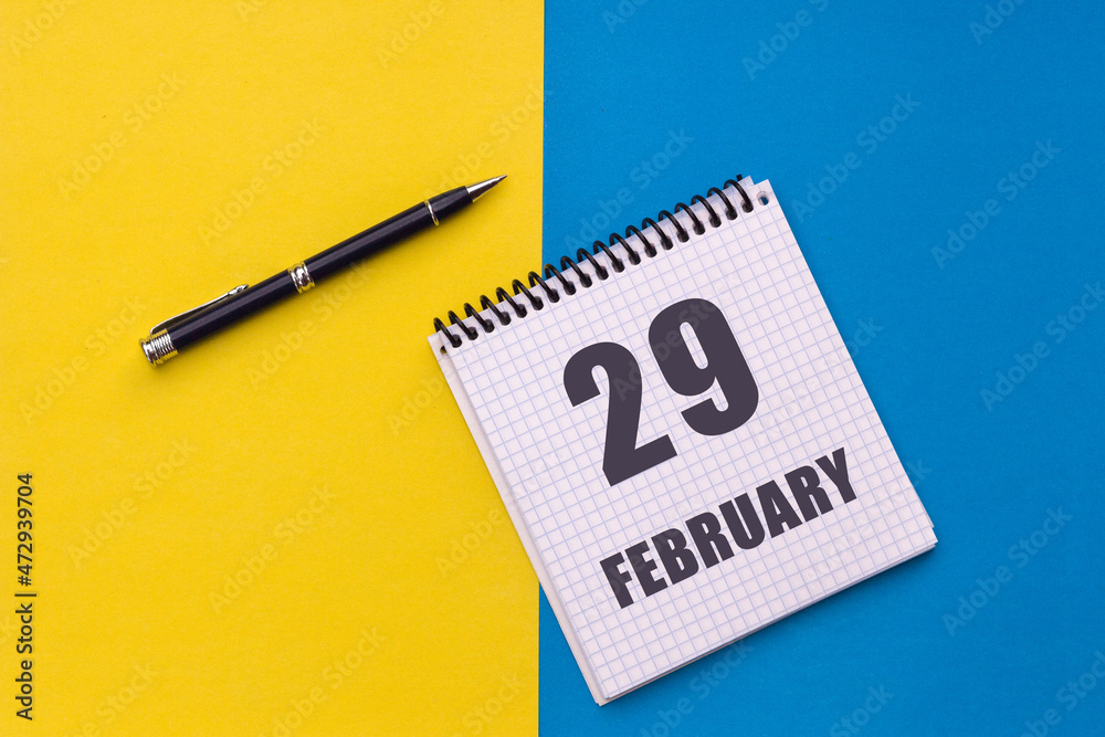February 29th. Day 29 of month. Calendar date. Notebook with a spiral and pen lies on a yellow-blue background. February 29th. Day 29 of month. Calendar date. Notebook with a spiral and pen lies on a yellow-blue background.