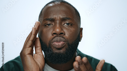 Closeup african man throwing air kiss from hand in grey background in studio.