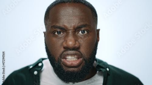 Portrait of angry african american man screaming in light background in studio.