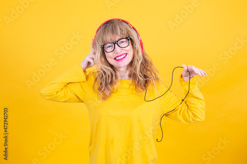 relaxed woman listening to music with headphones on yellow background photo