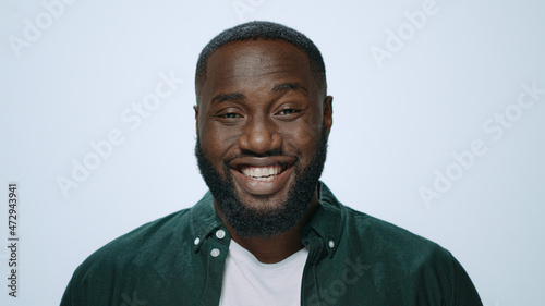 Portrait of happy african man laughing at camera on light background.