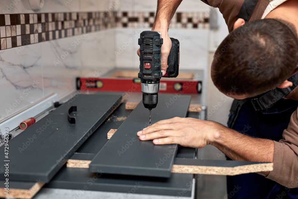 Handyman making kitchen wall cabinets in the apartment.