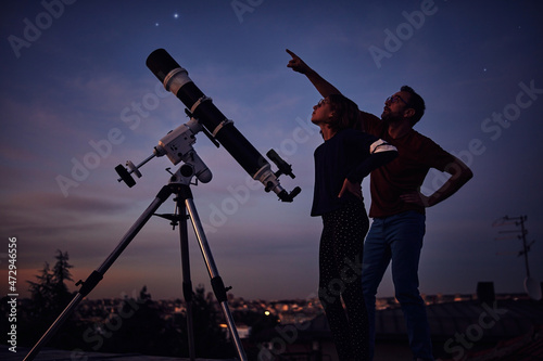 Silhouettes of father, daughter and astronomical telescope under starry skies. photo