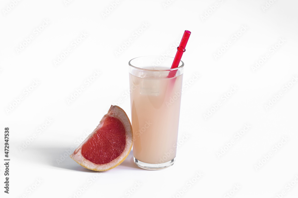 Grapefruit juice and a slice of grapefruit on a white background. Grapefruit juice in a glass glass with a red tube on a white background close-up Grapefruit juice and a slice of grapefruit on a white background. Grapefruit juice in a glass glass with a red tube on a white background close-up
