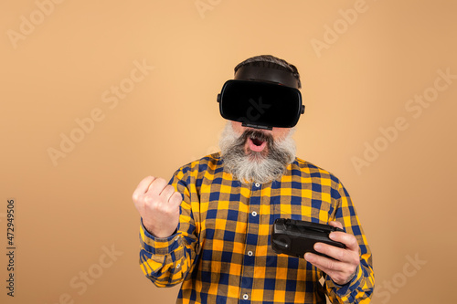 Cheerful man in 3D glasses plays with a joystick on a yellow background © jcalvera