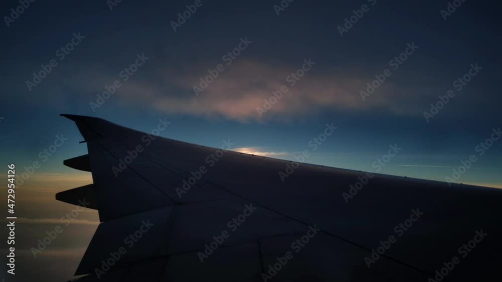Timelapse of flying plane in the evening sky filmed from the window. View of the jet wing moving on high speed with sunset on the background. Travelling around world by air vehicles. Holidays in trip. Timelapse of flying plane in the evening sky filmed from the window. View of the jet wing moving on high speed with sunset on the background. Travelling around world by air vehicles. Holidays in trip.
