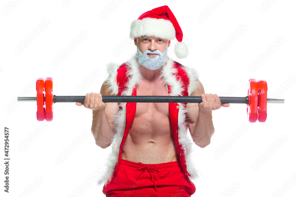 Christmas. Strong muscular Santa Claus with grey beard wearing christmas hat and red shorts is lifting a heavy barbell in a gym performing a workout isolated on white background.