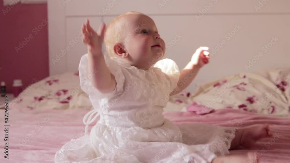 emotions baby in a dress on the bed,baby sitting in a dress and smiling emotions baby in a dress on the bed,baby sitting in a dress and smiling