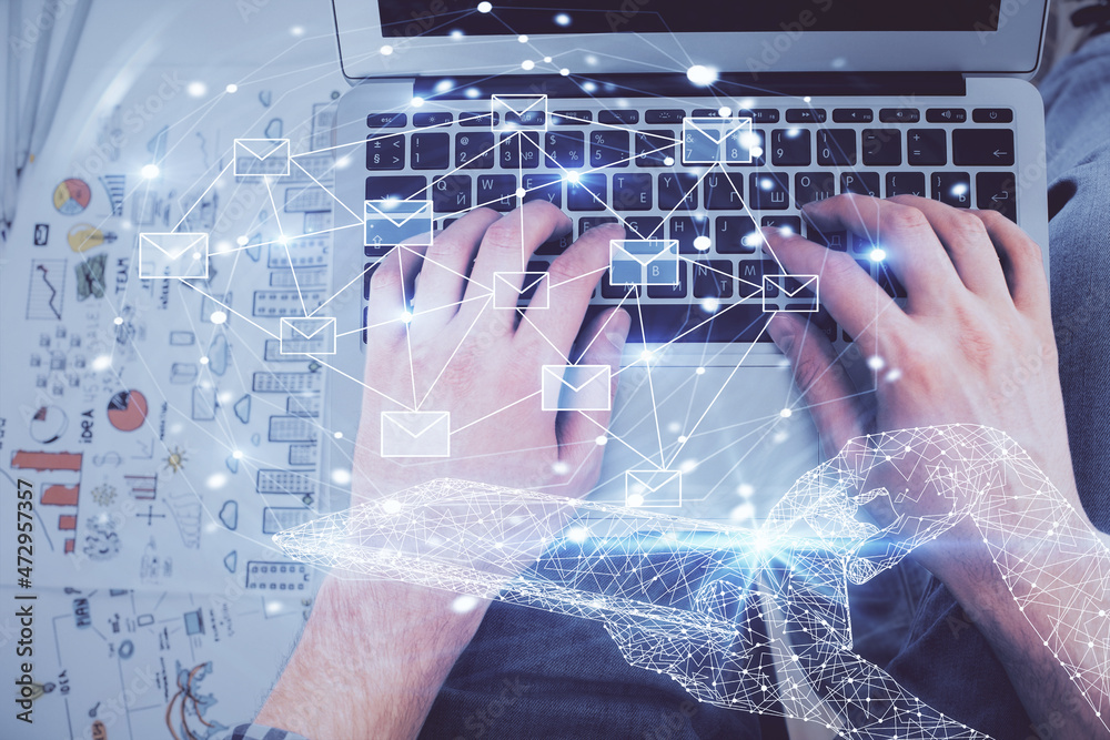 Double exposure of man's hands typing over computer keyboard and flying envelop hologram drawing. Top view. e-mail concept. Double exposure of man's hands typing over computer keyboard and flying envelop hologram drawing. Top view. e-mail concept.