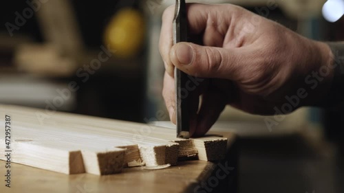 close up. a woodworker cuts out a dovetail on a pine board with a chisel. dovetail joinery is done with a hand tool. woodworker makes dovetail photo