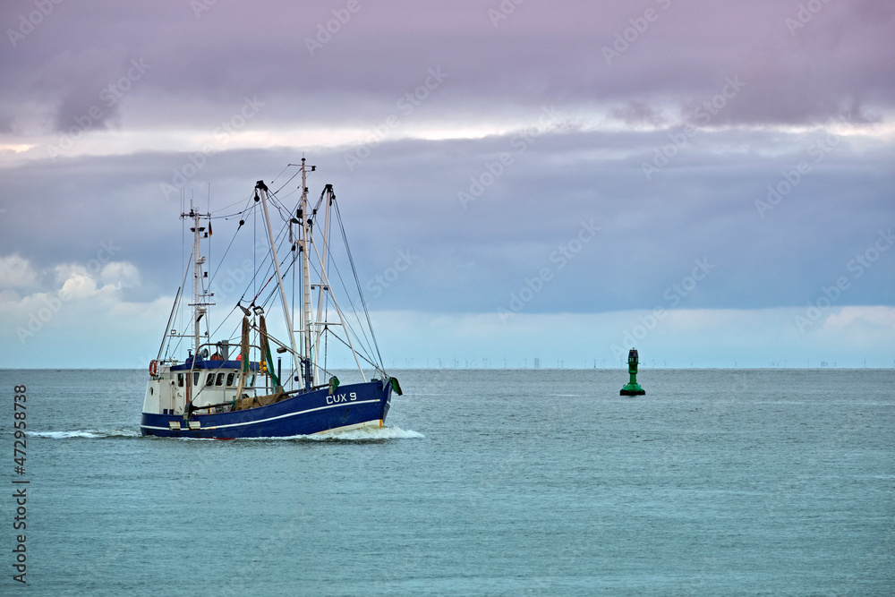 Fototapeta premium Ein Krabbenkutter ( CUX 9 RAMONA ) neben der Kugelbake an der Elbmündung in Cuxhaven.